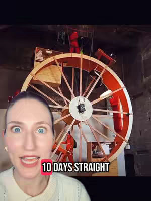 A woman with wide eyes and an open mouth is positioned in the lower left corner, appearing surprised. Behind her, a large wooden wheel is visible, with people in orange jumpsuits inside. The wheel has a complex structure of spokes, and the image is lit by a mix of artificial and natural light, creating a raw, industrial feel. Text overlayed at the bottom of the image says '10 DAYS STRAIGHT'.