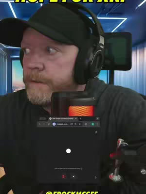A man in a black hat and headphones is looking with surprise, with text overlayed at the top. The man is in front of a digital screen. Below the screen is a microphone and a logo.