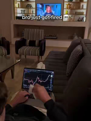 The image shows a person sitting on a couch, focused on a laptop displaying a financial chart. Behind them, a TV shows a woman speaking. The text overlay reads, bro just got fired.