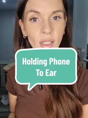 A woman with long brown hair looks directly at the camera. A teal speech bubble overlay reads, "Holding Phone To Ear". She is wearing a brown shirt and appears to be indoors.