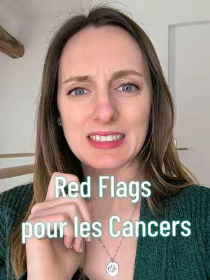 A woman with brown hair and blue eyes is centered in the frame, looking directly at the camera with a slight grimace. The words "Red Flags pour les Cancers" are overlaid on the image in a white, slightly transparent font. The woman is wearing a green top and a silver necklace with a round pendant. The background is plain, with a glimpse of a white door frame and a wooden beam.