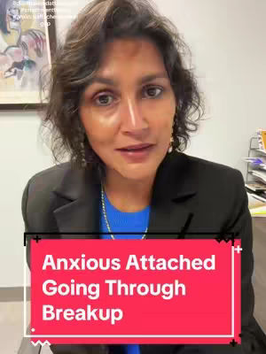 A woman with short, dark hair and a blazer is centered in a selfie-style shot. A text overlay appears in a red box at the bottom, while in the background, artwork and office supplies are visible.