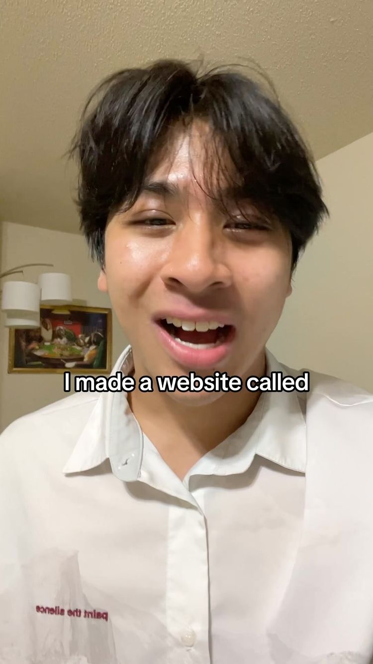 A young man with dark hair and a white collared shirt is the focus. He is smiling with his mouth open, suggesting speech or laughter. The background is a lightly colored wall. A framed artwork is partly visible behind him. Text overlay reads 'I made a website called'.