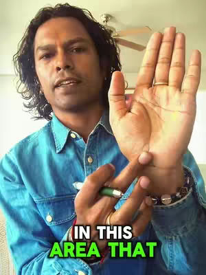 A man with dark hair and a blue shirt holds his open right palm towards the camera, with text overlayed on the bottom portion of the image. He's pointing to his wrist with a pen in his left hand.