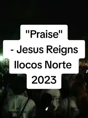 The image shows a cross-shaped white text overlay on a dark background with a crowd of people. The text overlay reads "Praise" - Jesus Reigns Ilocos Norte 2023. The background is blurred, suggesting a large gathering or event.