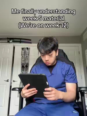 A young person sits in a black chair holding a tablet. The person is wearing blue scrubs, has dark hair. The background is a room with a door and a wall. Text is overlaid on the image.