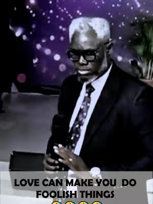 The cover image shows a man in a black suit, with a black tie and glasses. He is holding a microphone in a stage setting. The background is blurry with some stage lights. At the bottom, the text "LOVE CAN MAKE YOU DO FOOLISH THINGS" is displayed in white.