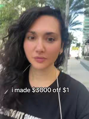 A woman with dark, curly hair is centered in the frame against a blurred outdoor background. She is wearing a black shirt with visible text and has a neutral expression. Text overlayed on the image reads, "i made $3000 off $1". The background appears to be a city street with trees and buildings.