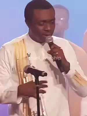 The cover image features a man speaking into a microphone. He is wearing a white outfit with a yellow shawl. The background is blurred, with a lighter figure behind him.
