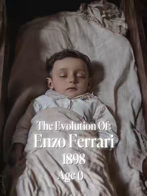 A vintage-style image of a sleeping baby in a wooden cradle, covered by a white sheet. Text overlays indicate the subject is Enzo Ferrari, with the year 1898 and 'Age 0' displayed beneath.