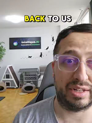 A man with glasses is in the foreground, looking at the camera and speaking. Behind him, a room is visible with a sign that says "Intellique.AI Innovation & Solutions", cat-shaped wall decor and a cat-themed shelter. The text "BACK TO US" is overlayed at the top.