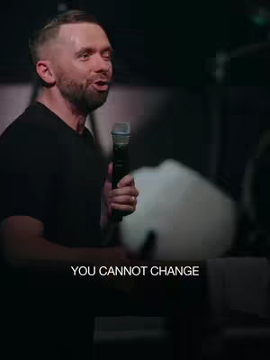 A man holding a microphone speaks with a passionate expression against a dark background. The text overlayed at the bottom says the words: "YOU CANNOT CHANGE”.