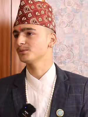 The cover image features a man in a formal attire, wearing a traditional Nepali cap. The man's face is in focus, he is looking towards left, and a small bindi is placed on his forehead adding a cultural touch. The background is blurred, suggesting a studio or indoor setting. Overall, the image has a formal and cultural feel.