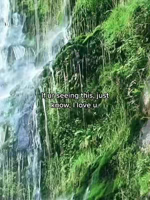 A lush green hillside is traversed by a powerful waterfall on the left. The water cascades rapidly. Text overlays offer a heartfelt message