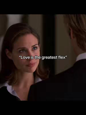 A still from a scene in a movie, a woman close up on the face speaking. Overlayed text reads "Love is the greatest flex". The background is blurred. The color palette is muted.