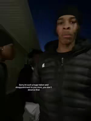 A young man is standing in front of a building at night. He is wearing a black beanie and a black puffy jacket. Text overlay suggests regret.
