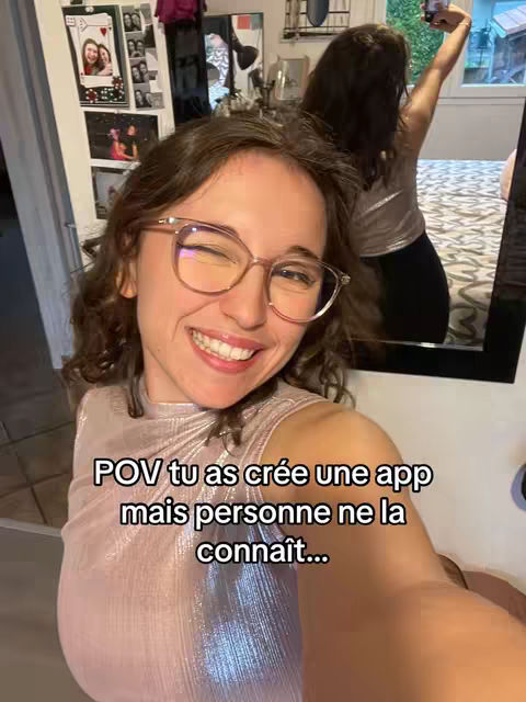A selfie-style shot features a woman in a sparkling top winking at the camera. Behind her is a mirror reflecting a continuation of the room, including another image of what appears to be the same woman holding up her phone to take a photo. Text overlayed on the image reads, "POV tu as crée une app mais personne ne la connaît..."