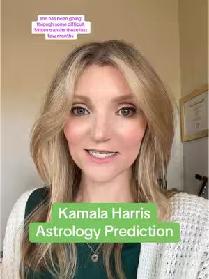 A woman with blonde hair and makeup is centered in the frame, smiling slightly. She's wearing a white sweater over a green top, and a small pendant is visible. Text overlays include a prediction about Kamala Harris and the phrase 'she has been going through some difficult Saturn transits these last few months'.