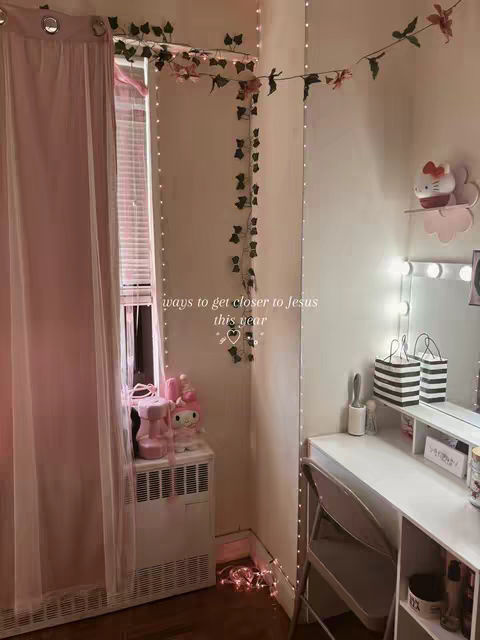 The cover image features a cozy, feminine room setting. A sheer pink curtain hangs on the left, framing a sunny window with blinds. The room's corner is adorned with string lights and a climbing plant, with a vanity area visible on the right side complete with a mirror, shelf, and a Hello Kitty figurine. Additional decorative items further enhance the aesthetic.