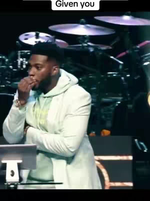 The cover image shows a man in an off-white coat with a hoodie, holding his hand up to his mouth and looking thoughtful. A drum kit is slightly visible in the background.