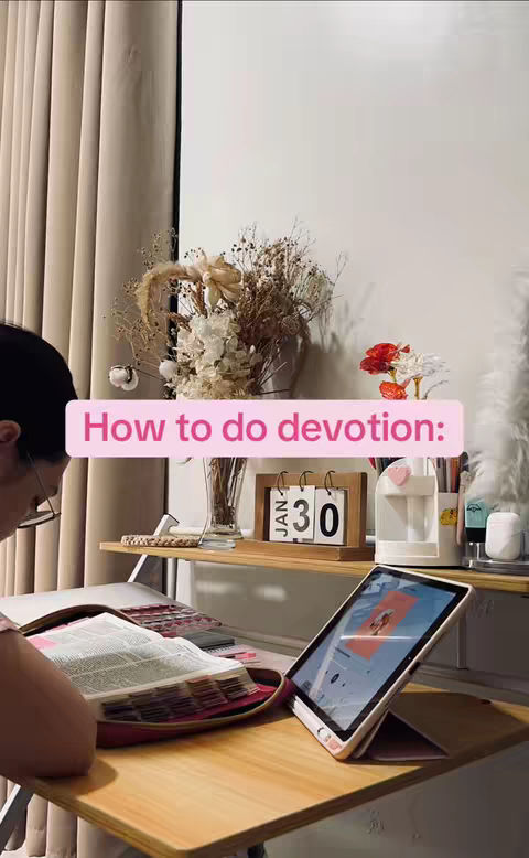 The cover image shows a person engrossed in a Bible study. A table holds an open book and a tablet with a Bible study app. The setting is softly lit with curtains, a shelf with a calendar, decorative flowers, and a water carafe. The text overlay reads 'How to do devotion:'.