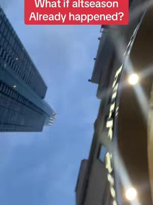 An urban shot, angled upwards, capturing the undersides of buildings against a cloudy sky. The frame focuses on architectural lines and the play of light and shadow, potentially hinting at an evening or overcast day. A red banner with white text is positioned in the upper part of the image.