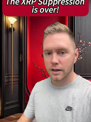 A man with short blond hair stands in front of a dark wooden door and a red upholstered wall. The man is facing the camera directly and has a neutral expression. Overlaid at the top of the frame is a red bar with white text. There is a side lamp to the left and what appears to be a branch with small white and pink flowers situated behind the man.