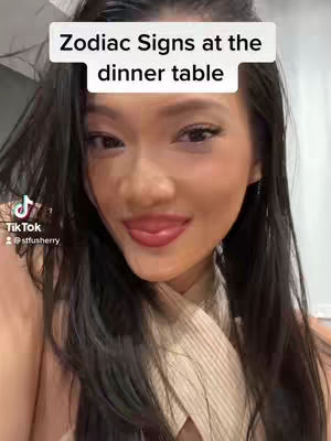 A woman with long black hair smiles, looking towards the camera. Above her is a white banner stating "Zodiac Signs at the dinner table". The TikTok logo and username '@stfusherry' are visible in the lower left.
