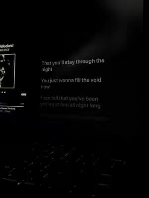 The cover image is a dark, possibly night time, scene. Lyrics of a song are displayed in a simple white font against the darkness. On the left side, a smaller image with a black and white photo is shown. The overall composition is minimalistic, using a limited color palette.