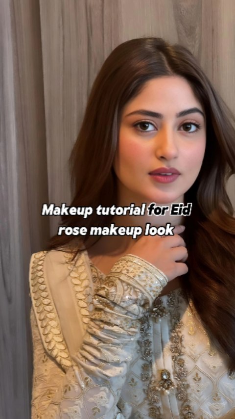 The cover image showcases a woman with light skin who is looking directly at the camera. She has brown hair, and is wearing an embroidered cream-colored outfit. The background is a basic, neutral wall color. A text overlay provides the video's title and a description of the makeup style.
