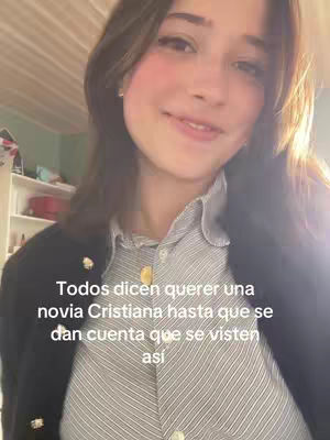 A young woman with brown hair and fair skin poses for a selfie, smiling slightly. She wears a striped button-up shirt under a black blazer, with a hint of a white ceiling and a cabinet in the background. Text is overlaid at the bottom, written in white font.