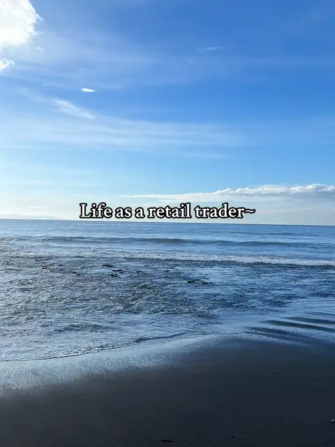 A serene landscape with a vast blue sky above a dark beach and ocean. The text "Life as a retail trader~" is centered and overlaid on the image.