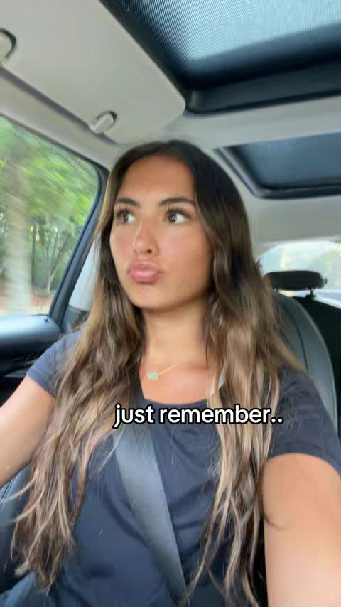 The cover image is a selfie of a young woman sitting in the driver's seat of a car. She has long, wavy brown hair, fair skin, and is wearing a dark t-shirt. The focus is on her face, and she is looking towards the camera with a slight pout. The background shows the inside of the car, including the dashboard, steering wheel, and window. The lighting appears to be natural, with the sun illuminating her face. The overall composition is casual and intimate.