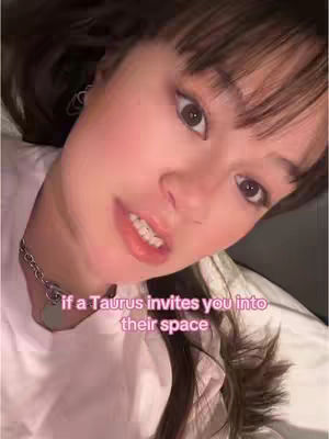 A selfie-style shot with a woman facing the camera, lying down on a bed with a white sheet and pillow in the background. Text overlayed on the image in a pink font.