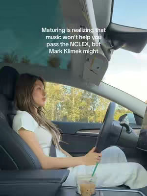 A woman in a white top is driving a vehicle, partially visible. The interior is modern, with a light-colored dashboard. Daylight streams in, and text overlays the image.