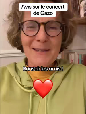 A woman with glasses smiles at the camera wearing a light green hoodie. Text overlays read "Avis sur le concert de Gazo" at the top and "Bonsoir les amis !" at the bottom, with a red heart emoji in the center.