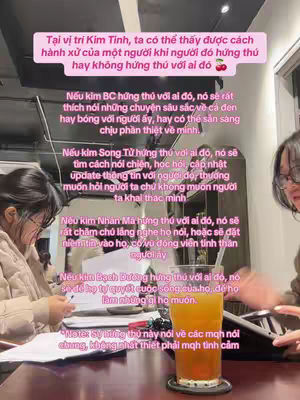 The image shows a woman sitting at a table with a glass of orange liquid, likely a drink, in front of her. She is wearing glasses and has dark hair. The top of the image is filled with text in a pink rectangle. The content seems to be related to astrology as suggested by the caption.