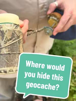 The image shows a close-up of two hands holding geocaching containers. One container is a camouflage-wrapped cylinder, while the other is a small, round container. A speech bubble with text is overlaid, asking "Where would you hide this geocache?"