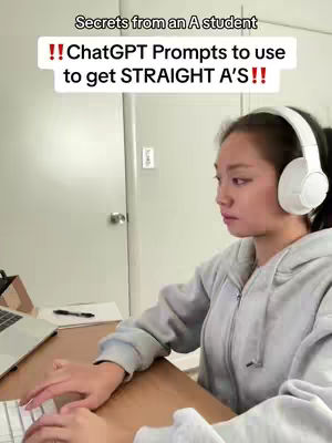 A young woman with long dark hair and white headphones sits at a wooden desk, typing on a keyboard. A laptop, pen, and notepad are visible on the desk. The background includes a white door and wall. Text overlays at the top of the image, using bold white text, that say, "Secrets from an A student" and "!! ChatGPT Prompts to use to get STRAIGHT A'S!!"