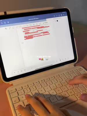 The cover image shows a tablet with a bright screen, displaying a document with red highlighted lines. The tablet is connected to a white keyboard. The focus is on the tablet and keyboard, with a pair of hands typing on the keyboard. In the background, a blurred desk provides context.