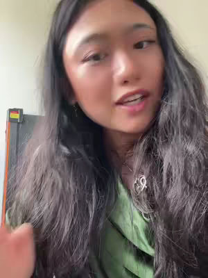 The cover image is a selfie featuring a young woman with long dark hair, a green top, and a necklace. She is positioned in front of a somewhat blurred background, appearing to be indoors. The lighting seems natural, with the focus on her face and upper body as she speaks. The overall composition is simple and direct, with soft colors.