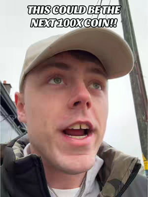 A man in a baseball cap and jacket looks upwards with an open mouth. Text overlay at the top reads, 'THIS COULD BE THE NEXT 100X COIN!!'. The background is blurred, suggesting an outdoor setting, likely near a road.