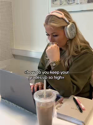 A woman with long blonde hair is seated at a desk with a laptop and a beverage. She's wearing a headset and looking down, as if in thought. Text on the screen asks how to keep grades up.