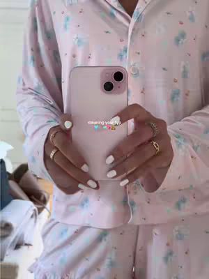 A person is holding a phone in front of their body. The person is wearing a pink pajama set with a floral pattern. The phone's screen has the text overlayed on it while the person's hands are visible as they hold the phone.
