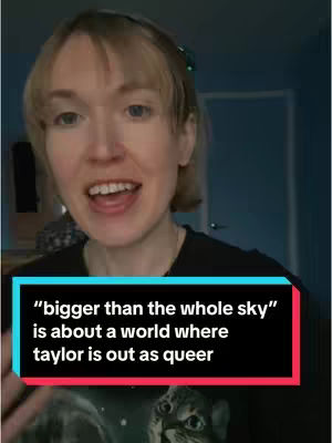 A woman with blonde hair is centered in the frame, looking slightly to the left with an open mouth as if speaking or singing. The background shows a glimpse of a door and a muted blue wall. A text overlay in a rectangular box with a teal background and a red border in the bottom portion of the frame.