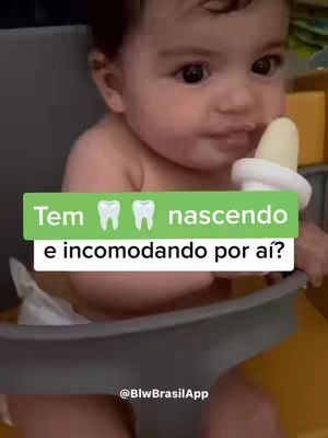 A baby sitting in a booster seat. The baby is facing towards the camera and has a popsicle in its mouth. There is a green bar with white text in the middle of the image.