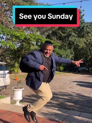 A man in a suit jumps in the air with a joyful expression, pointing with his right hand and extending his left arm to the side. The background shows a green, leafy environment with a white car and a building. Text that reads 'See you Sunday' is overlayed on the image.