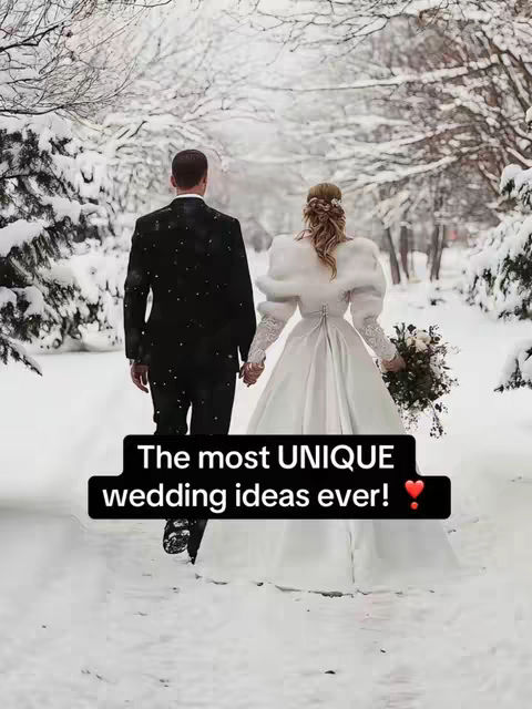 A couple, viewed from behind, walks hand-in-hand down a snow-covered path through a winter wonderland. The man wears a black suit, and the woman is in a white wedding dress with a matching fur shawl. A text overlay reads 'The most UNIQUE wedding ideas ever! ❤️'.