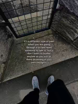 The image shows an overhead perspective of someone standing in front of what appears to be a metal grate or gate. The person's legs and feet are visible, wearing light-colored sneakers. The scene has an overcast or desaturated color palette, lending a somber mood. Text overlaying the image conveys a message about the pain of wanting to talk, but not wanting to burden others.
