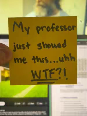 A close-up shot of a yellow sticky note is featured. The note, held by a hand, displays handwritten text in black marker stating, 'My professor just showed me this...uhh WTF?!' Background elements are partially visible: an out-of-focus person behind the note and a computer screen showing what appears to be a soccer field.